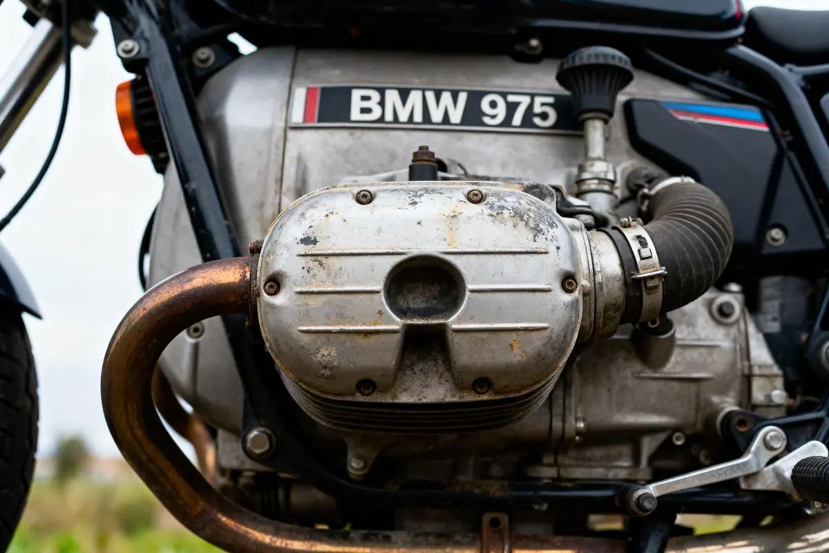 Gros plan du moteur d'une moto BMW 975, avec des détails visibles de la mécanique et tuyauterie.