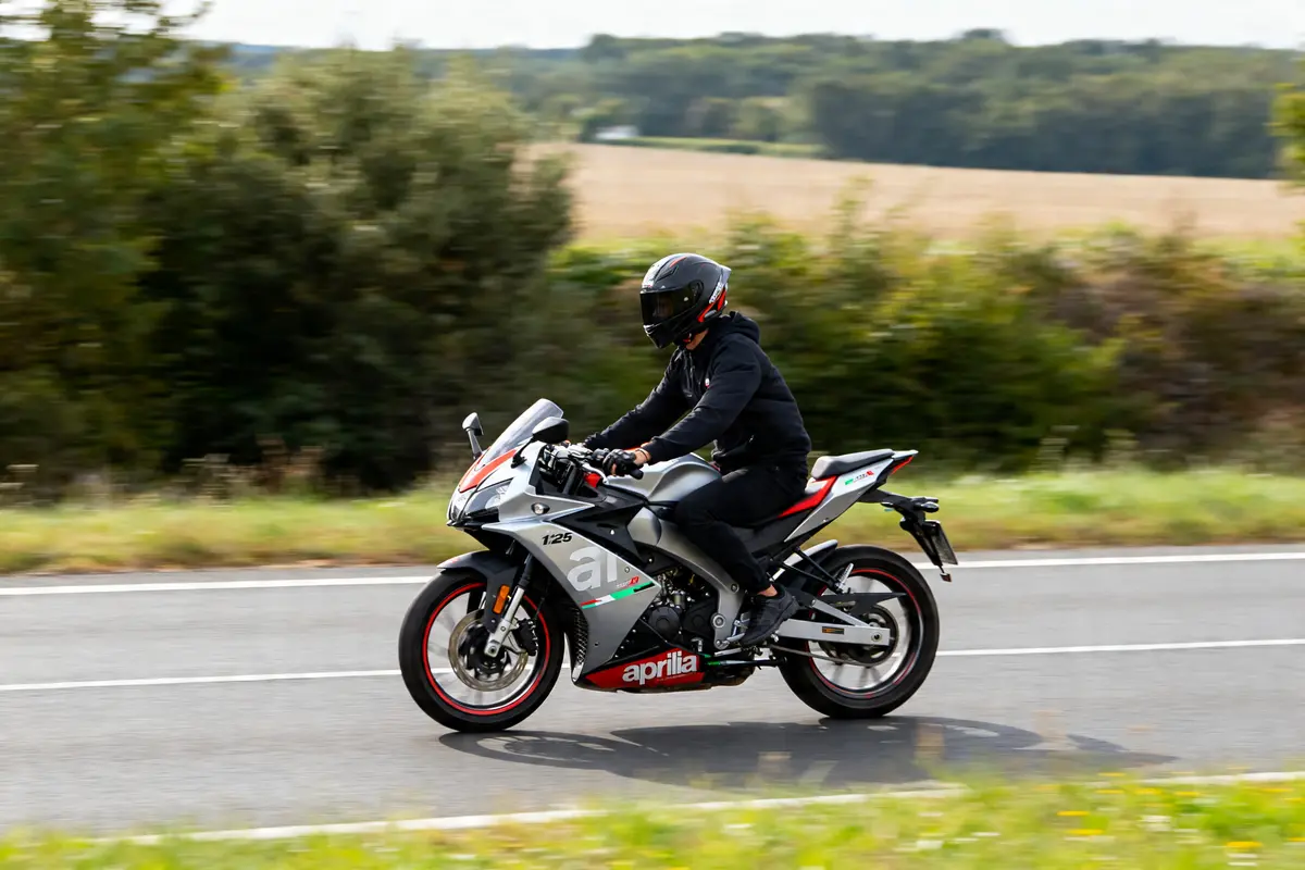 Motard sur Aprilia SR GT 125 roulant rapidement sur route pour débridage vitesse max