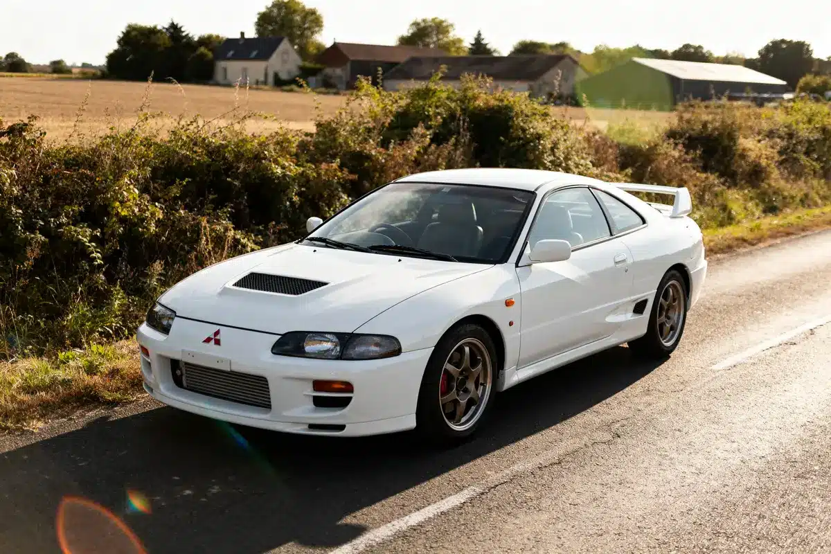 Voiture blanche Mitsubishi FTO coupé stationnée sur une route de campagne ensoleillée