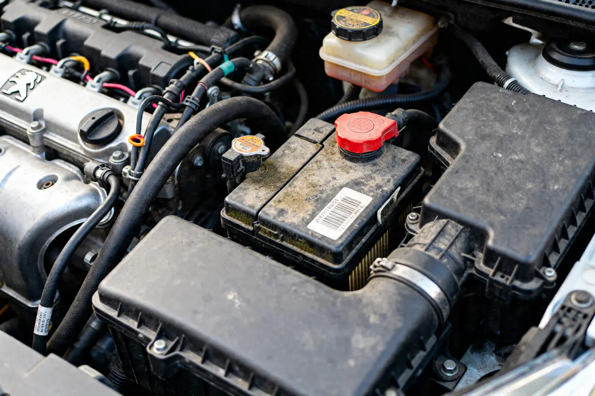 Moteur d'une Peugeot 208 avec batterie visible suggérant un défaut moteur 208 possible