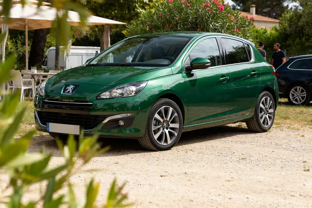 pexels-michal-pech-213601-757318 (1) Voiture Peugeot 308 verte garée sur un chemin de gravier entouré de verdure