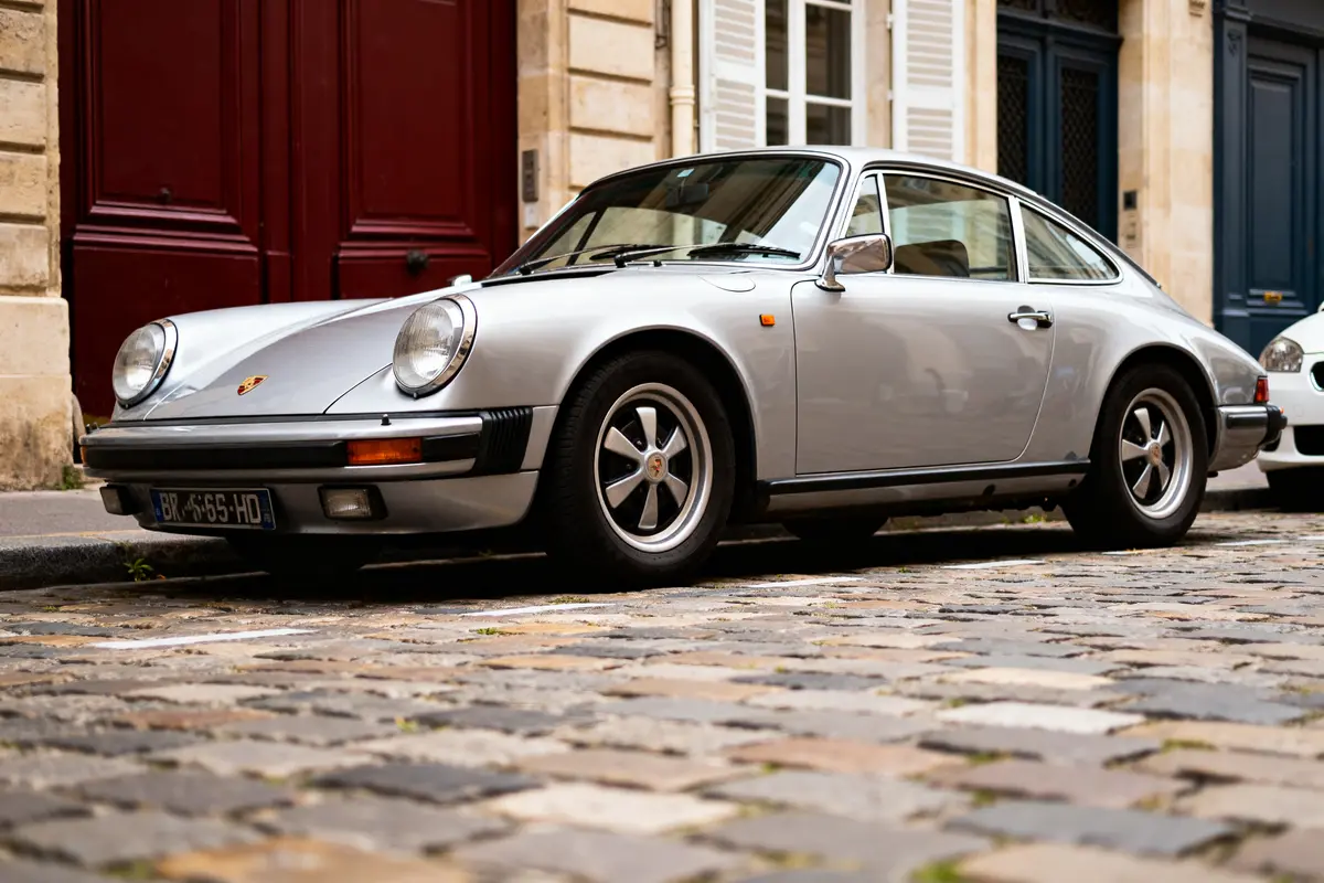 pexels-michal-pech-213601-757318 (1) Porsche ancienne argentée garée sur une rue pavée devant des bâtiments historiques
