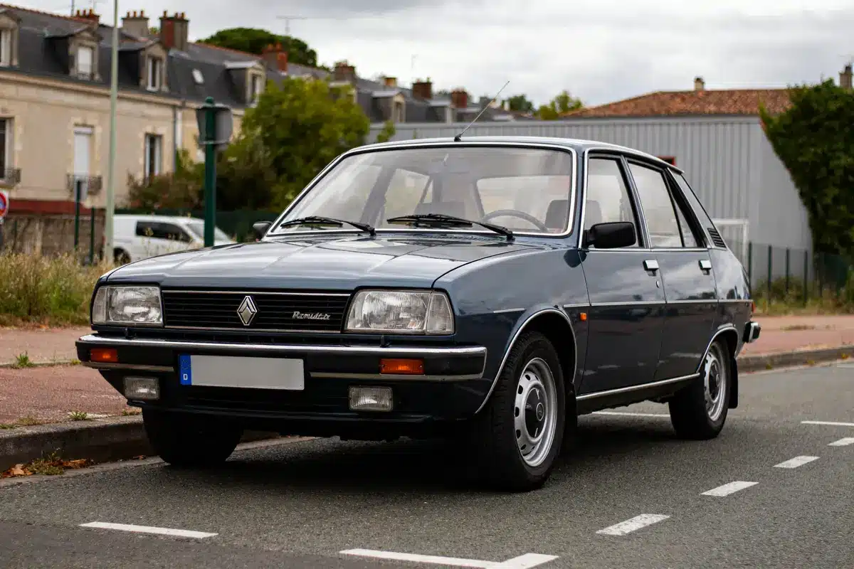 Renault 18 bleue ancienne garée sur une rue résidentielle devant des maisons
