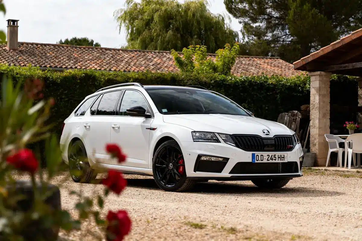 Voiture blanche Skoda Octavia VRS Auto stationnée sur une allée devant une maison.